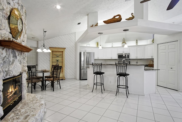 kitchen with a center island, a breakfast bar area, lofted ceiling, a fireplace, and stainless steel appliances