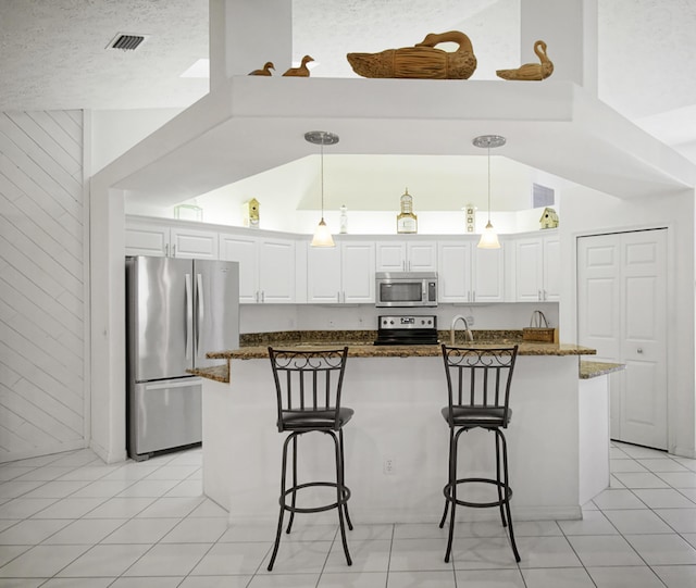 kitchen featuring white cabinetry, dark stone countertops, a breakfast bar area, and appliances with stainless steel finishes