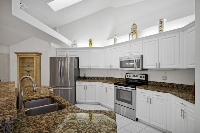 kitchen with a skylight, white cabinetry, stainless steel appliances, and a sink