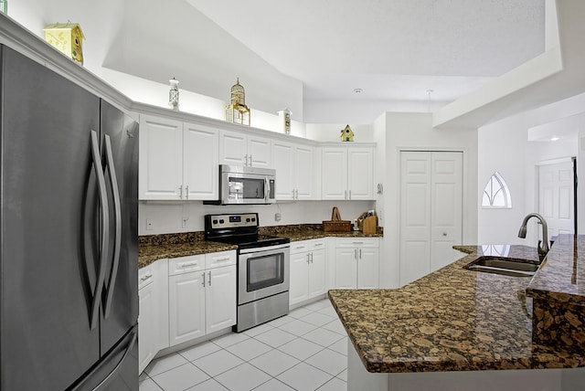 kitchen with a sink, dark stone countertops, white cabinetry, stainless steel appliances, and light tile patterned flooring