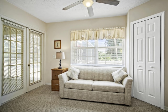carpeted living room featuring ceiling fan and a textured ceiling