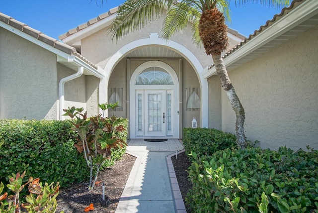 doorway to property with stucco siding and a tile roof