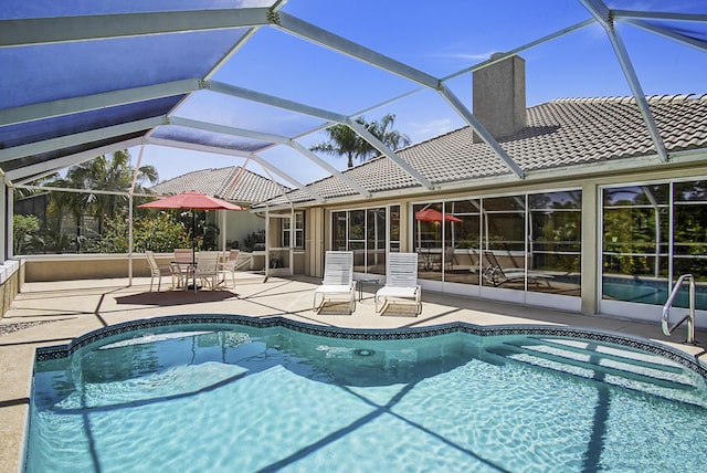 outdoor pool with glass enclosure and a patio area