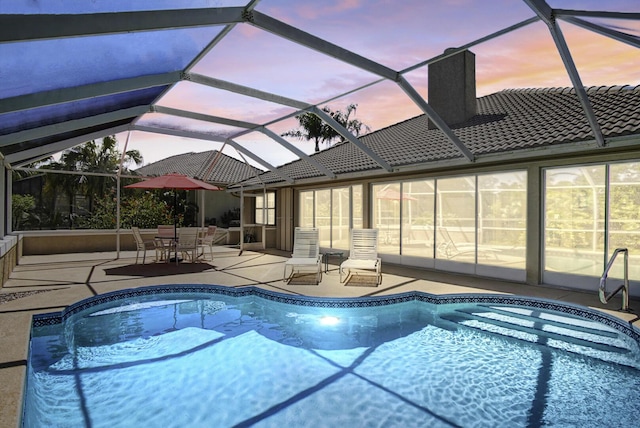 pool with glass enclosure and a patio area