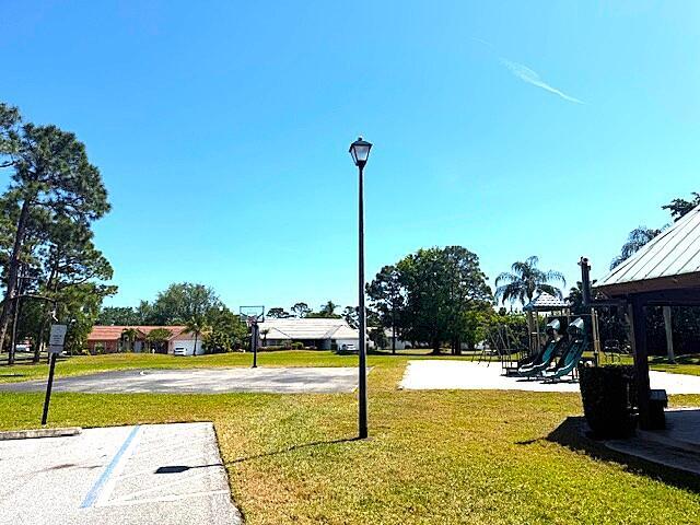 surrounding community with playground community, a yard, and community basketball court