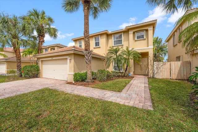 mediterranean / spanish house with stucco siding, driveway, a front lawn, a tile roof, and fence