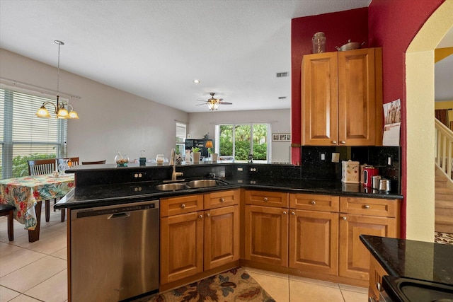 kitchen with brown cabinets, a sink, dark stone countertops, arched walkways, and appliances with stainless steel finishes