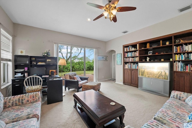 carpeted living area with arched walkways, visible vents, and a healthy amount of sunlight