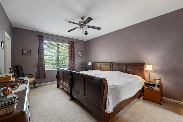 bedroom featuring light colored carpet, baseboards, and ceiling fan