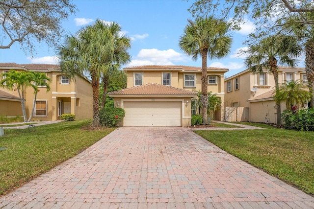 mediterranean / spanish house featuring stucco siding, a front lawn, a tile roof, decorative driveway, and fence