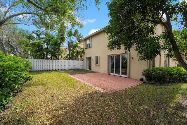 back of property with a patio, a yard, fence, and stucco siding