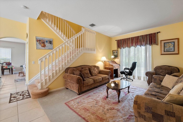 tiled living area featuring visible vents, arched walkways, baseboards, and stairs