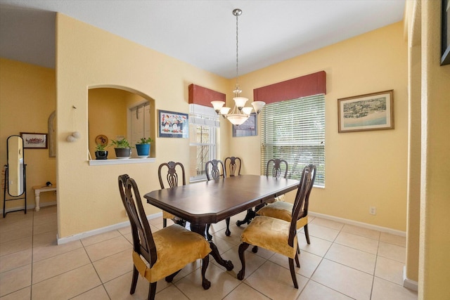 dining space with a notable chandelier, light tile patterned flooring, baseboards, and arched walkways