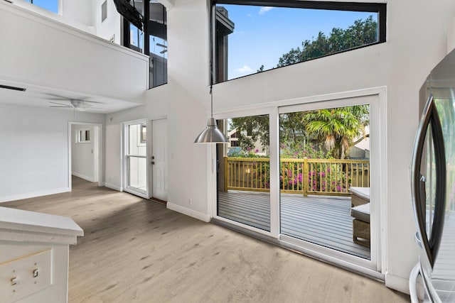 interior space with ceiling fan, baseboards, wood finished floors, and a towering ceiling