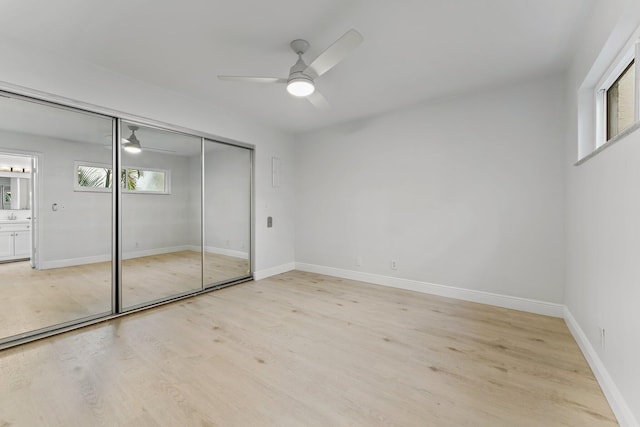 unfurnished bedroom with ceiling fan, light wood-style floors, a closet, and baseboards