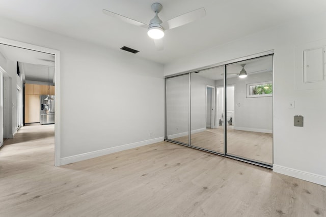 unfurnished bedroom featuring stainless steel fridge with ice dispenser, visible vents, light wood finished floors, and baseboards