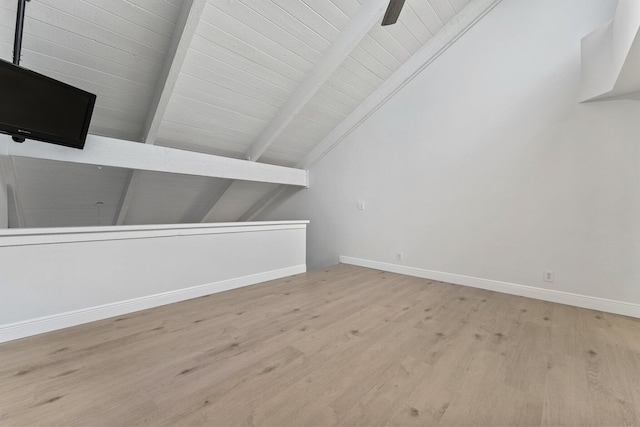 additional living space with baseboards, wood finished floors, and vaulted ceiling with beams