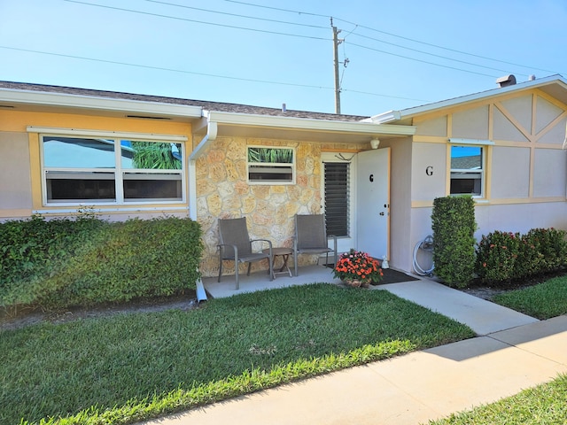 view of front of house with stucco siding, a front lawn, and a patio area