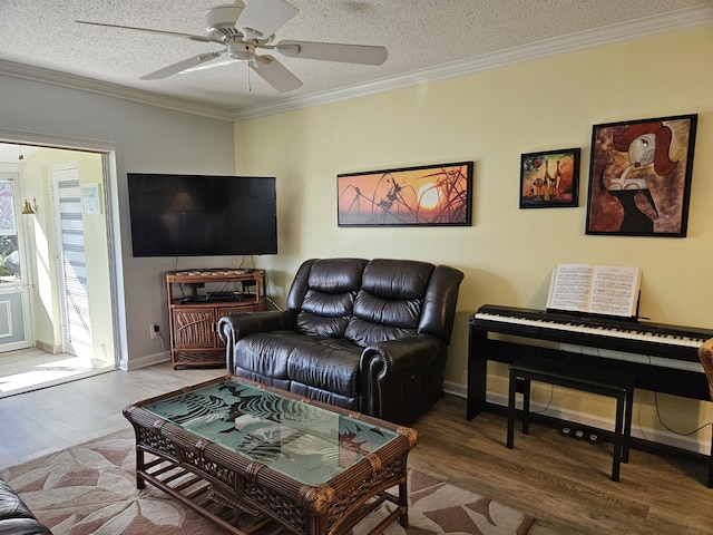 living area with crown molding, baseboards, ceiling fan, wood finished floors, and a textured ceiling