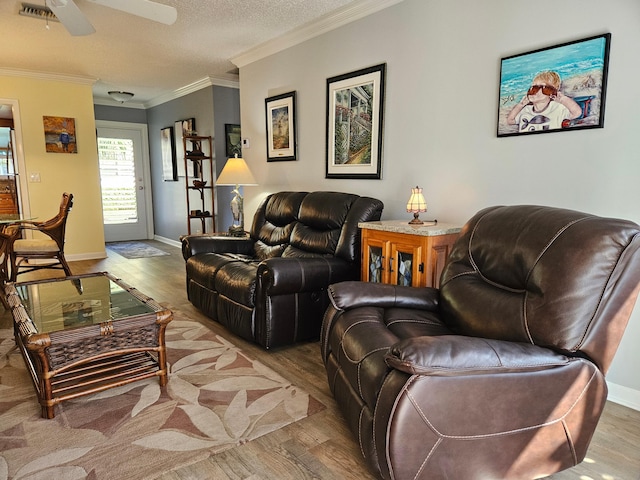 living room with a ceiling fan, wood finished floors, visible vents, a textured ceiling, and crown molding