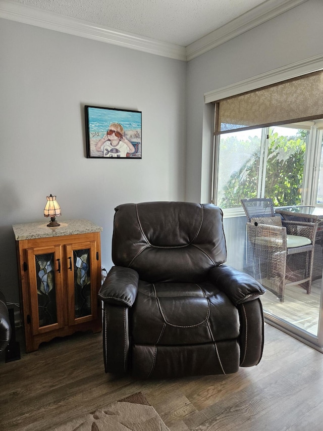 sitting room featuring a textured ceiling, wood finished floors, and ornamental molding