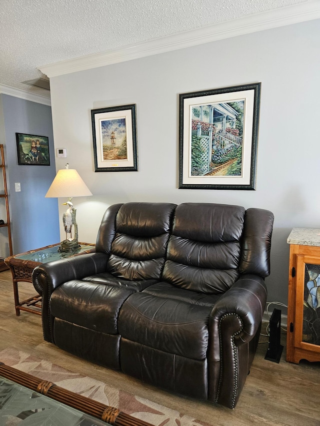 living area with wood finished floors, a textured ceiling, and ornamental molding