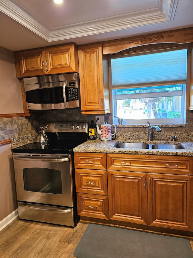 kitchen featuring a sink, appliances with stainless steel finishes, crown molding, and a healthy amount of sunlight