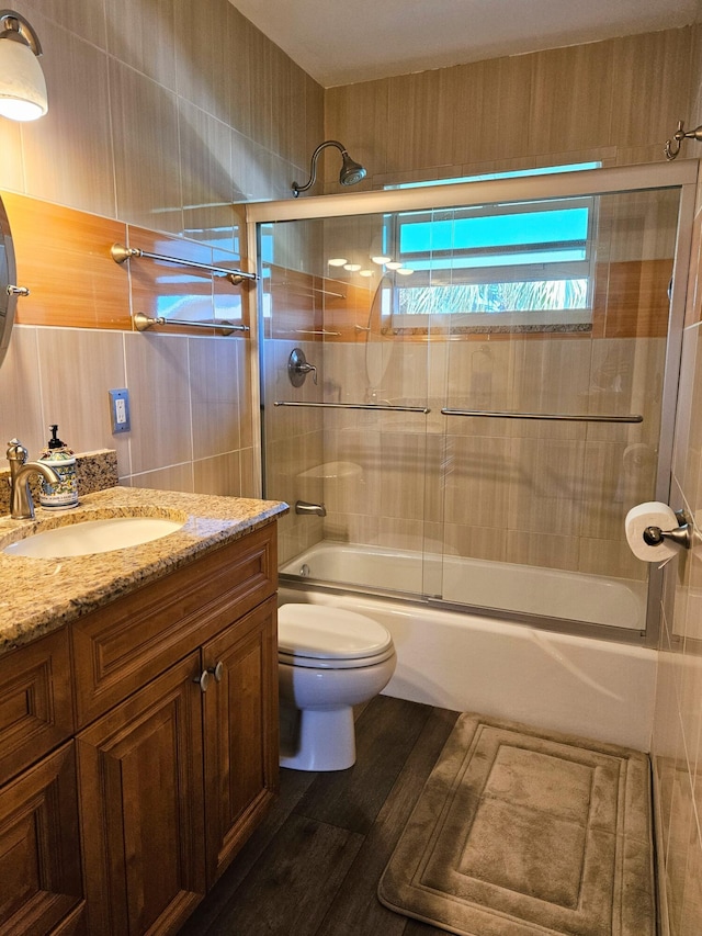 bathroom with vanity, toilet, wood finished floors, and combined bath / shower with glass door