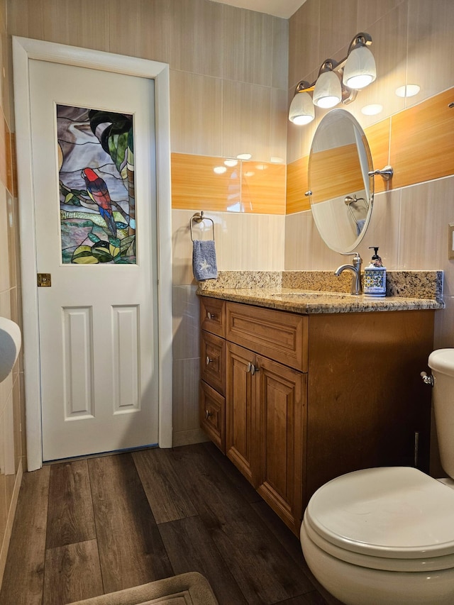 bathroom featuring vanity, tile walls, toilet, and wood finished floors