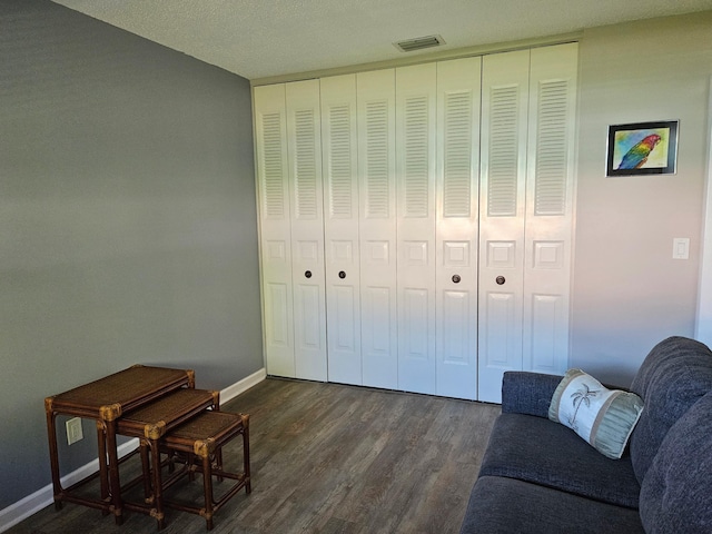 living area with dark wood-type flooring, visible vents, and baseboards