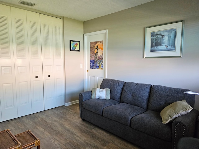 living room with dark wood-type flooring, baseboards, and visible vents