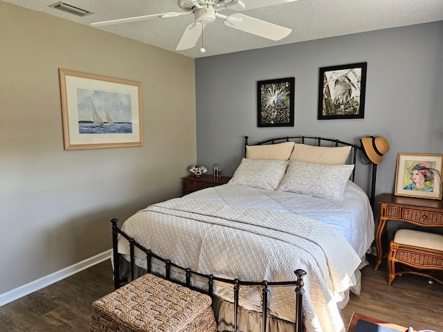 bedroom with wood finished floors, visible vents, baseboards, ceiling fan, and a textured ceiling