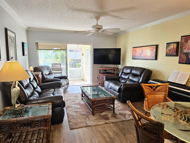 living area with a ceiling fan, a textured ceiling, wood finished floors, and ornamental molding