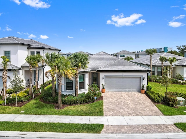 view of front of property featuring stucco siding, an attached garage, a tile roof, and decorative driveway