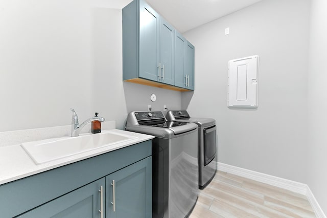 laundry area featuring washing machine and clothes dryer, cabinet space, a sink, and baseboards