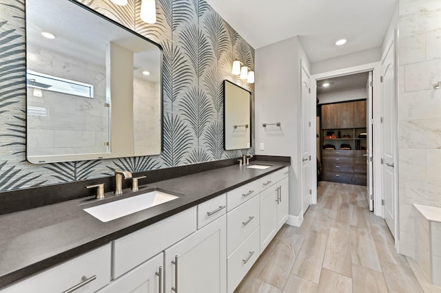 bathroom featuring wallpapered walls, a sink, double vanity, and recessed lighting