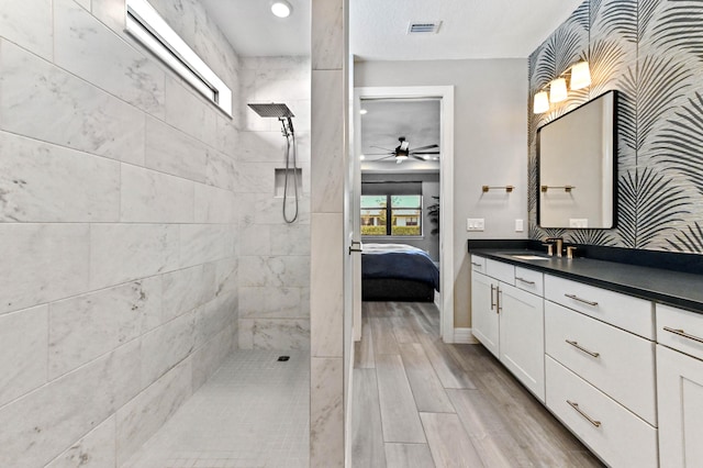 ensuite bathroom with visible vents, connected bathroom, vanity, wood tiled floor, and a walk in shower