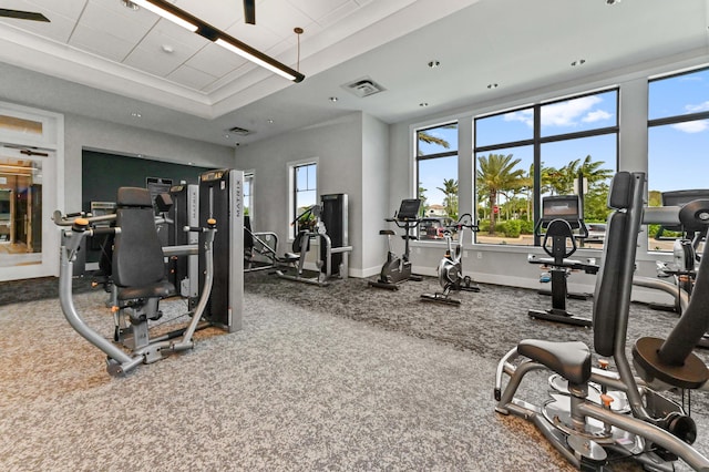workout area featuring a tray ceiling, baseboards, and visible vents
