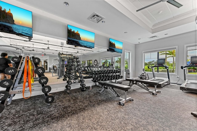 gym with a tray ceiling, baseboards, and visible vents