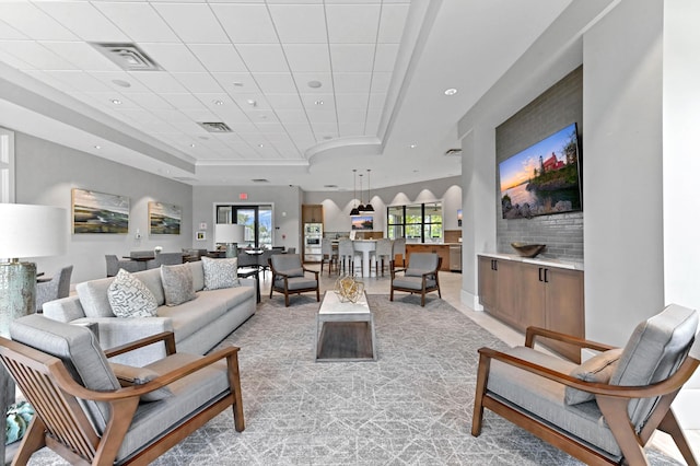 living room featuring recessed lighting, light carpet, a tray ceiling, and visible vents