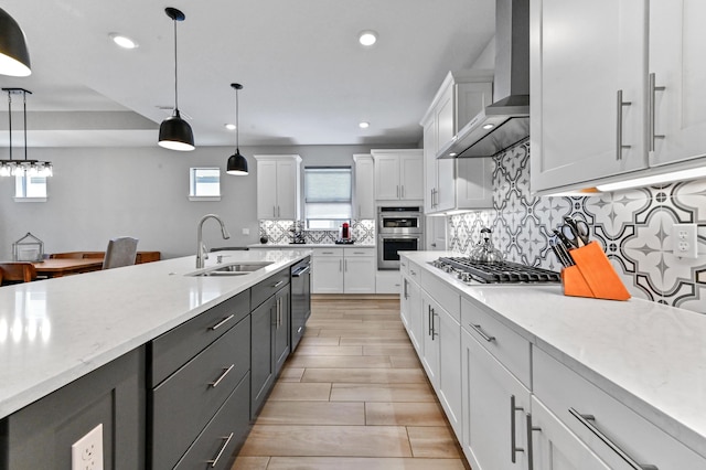 kitchen featuring white cabinetry, a sink, wall chimney exhaust hood, and appliances with stainless steel finishes