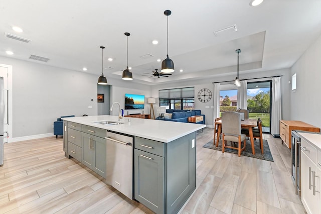 kitchen featuring a tray ceiling, a sink, gray cabinetry, and dishwasher