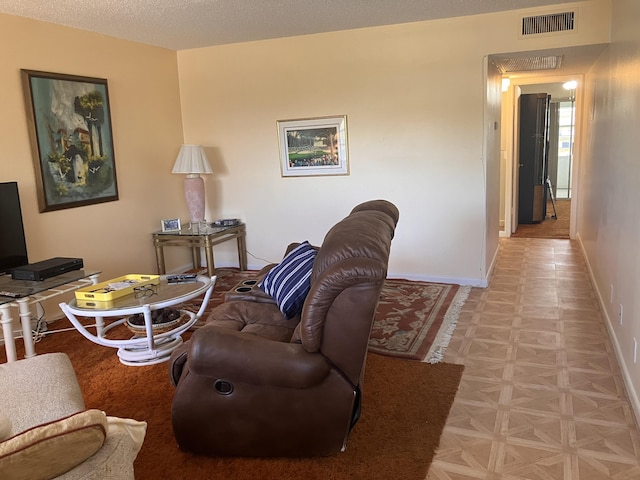 living room with baseboards, visible vents, and a textured ceiling