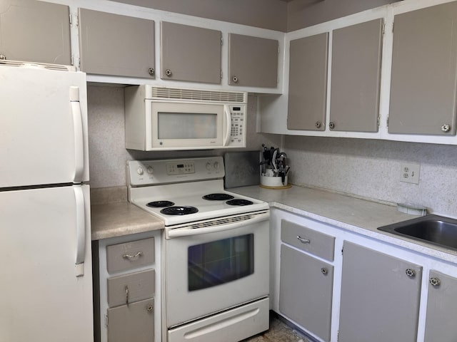 kitchen with light countertops, gray cabinets, and white appliances