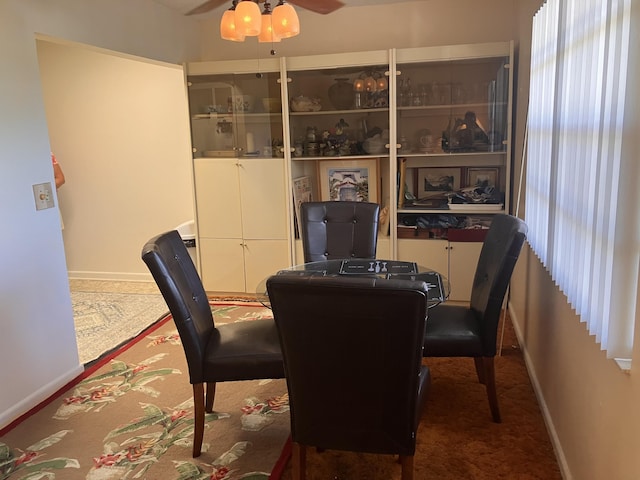 carpeted dining area with baseboards and ceiling fan