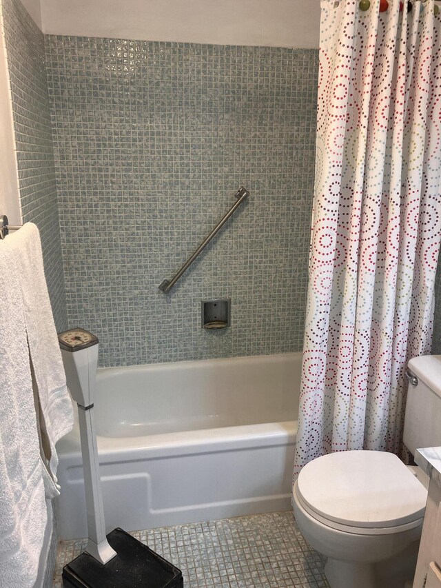bathroom featuring tile patterned floors, shower / bathtub combination with curtain, and toilet