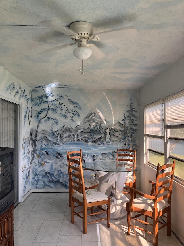 dining space featuring ceiling fan and a textured ceiling