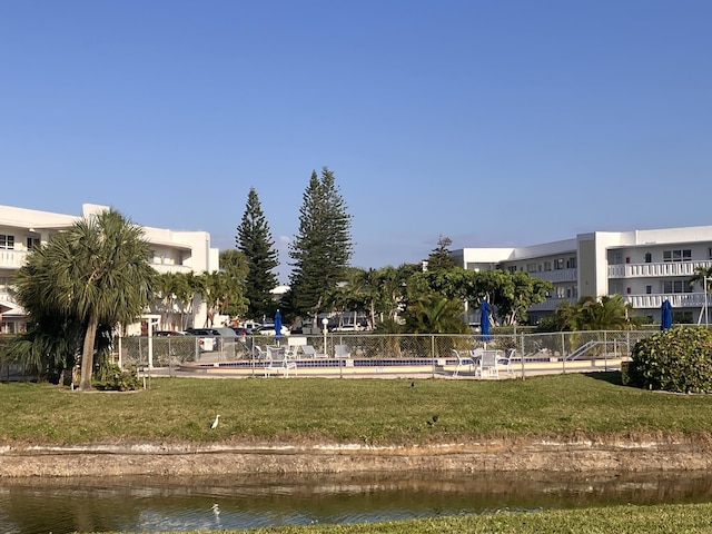 view of community featuring a water view, fence, and a lawn