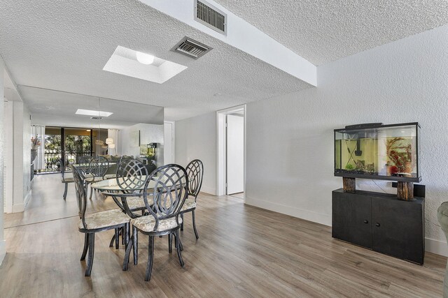 dining area featuring visible vents, a textured ceiling, and wood finished floors