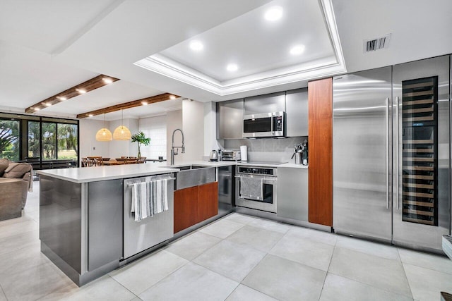 kitchen with visible vents, modern cabinets, a sink, appliances with stainless steel finishes, and a peninsula